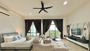 A modern living room with a sofa, a TV, and a ceiling fan. - Molek Regency By Stayrene (Plentong)