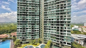 A high-rise building with multiple balconies, a swimming pool, and a landscaped area. - Molek Regency By Stayrene (Plentong)