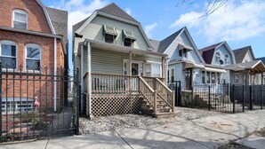 A row of townhouses with a shared driveway, a gated entrance, and a small front yard with gravel.
