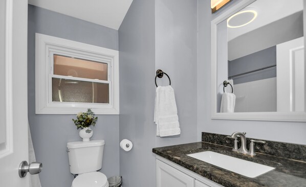 Une salle de bain moderne avec des toilettes, un lavabo et un miroir.