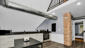 A modern kitchen with a stainless steel range hood, white cabinetry, and a black countertop.