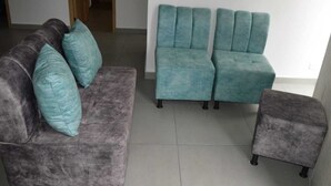 Un soggiorno con un divano grigio, cuscini color petrolio e un divano componibile color petrolio.