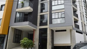 Un edificio moderno a più piani con balconi, ampie finestre e un rivestimento in cemento e bianco.