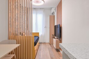 Ein gemütlicher Raum mit Bett, Fernseher, kleinem Tisch und Schreibtisch.