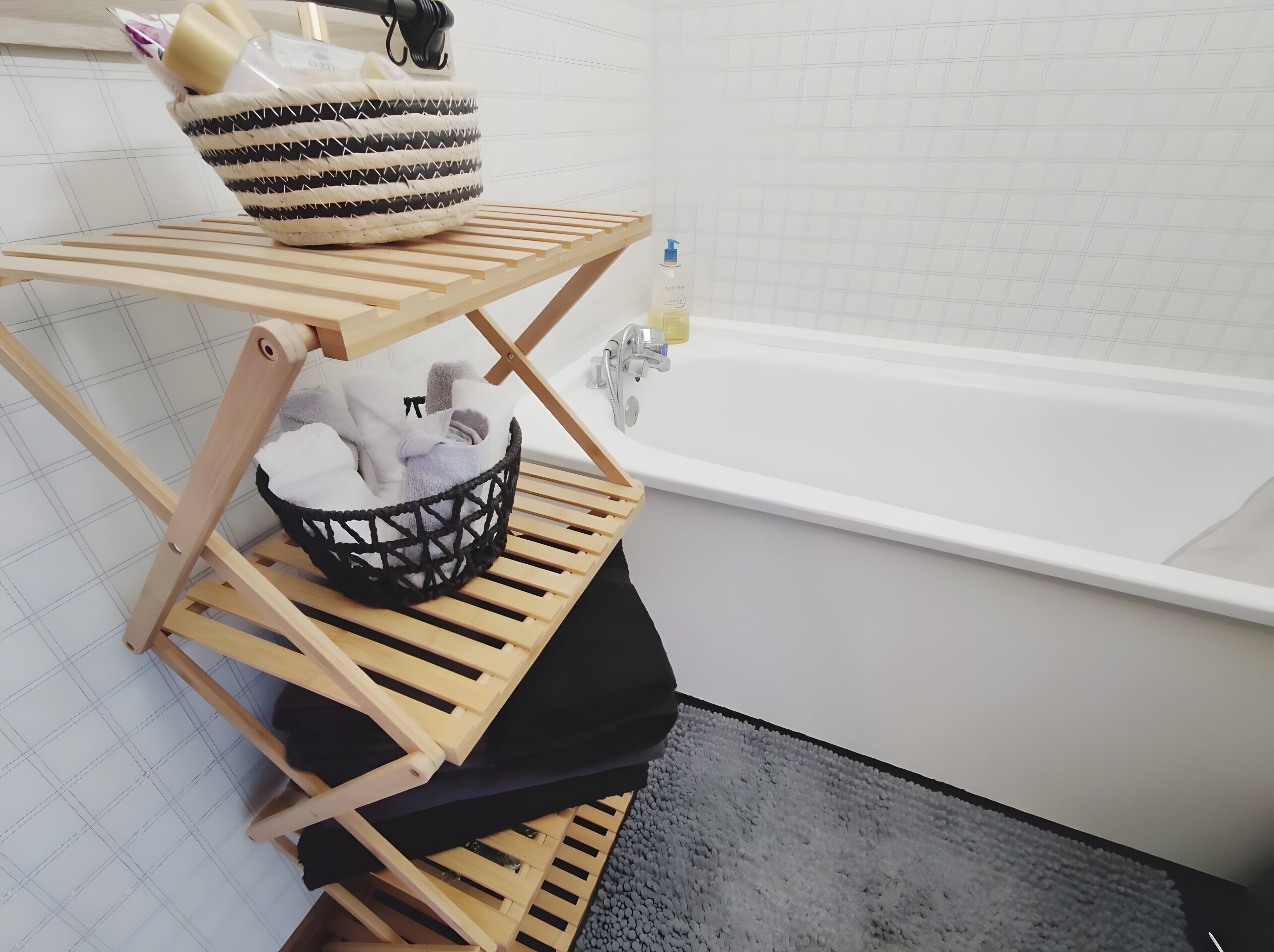 Ein Badezimmer mit einem Holzregal, auf dem ein Korb und eine Handseifenflasche stehen.