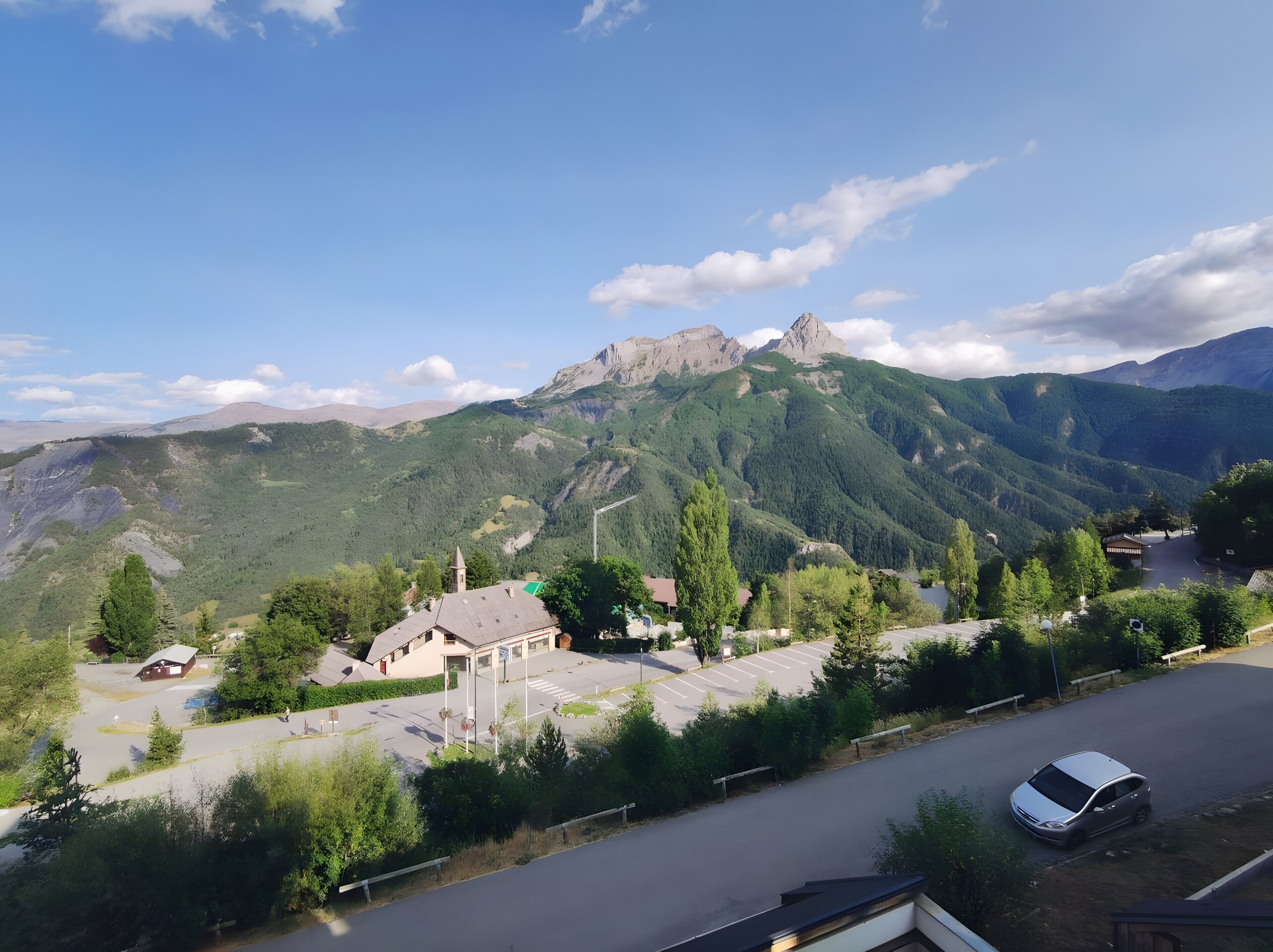 A mountainous landscape with a road, a parking lot, and a few buildings.
