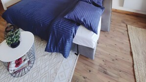 Un dormitorio moderno con una cama, mesitas de noche, una pequeña mesa redonda con una planta y una alfombra estampada.