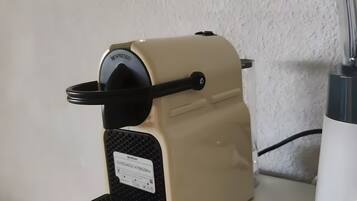 Une machine à café posée sur un plan de travail de cuisine, avec un mur blanc à texture visible en arrière-plan.