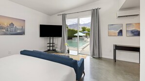 A modern hotel room with a bed, a TV, a desk, and a view of a swimming pool. - Private Pool and Spa in Palm Springs with Mid Century Style and Mountain Views (Palm Springs)