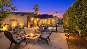 An outdoor patio area with a fire pit, seating, and a pool. - Private Pool and Spa in Palm Springs with Mid Century Style and Mountain Views (Palm Springs)