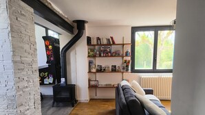 Ein gemütliches Wohnzimmer mit Kamin, Bücherregal und großem Fenster.