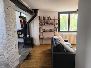 A cozy living room with a fireplace, a bookshelf, and a large window.