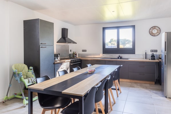 A modern kitchen with a dining area, a high chair, and a large window.
