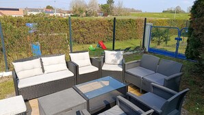 Ein Sitzbereich im Freien mit Korbmöbeln und einem Glastisch.