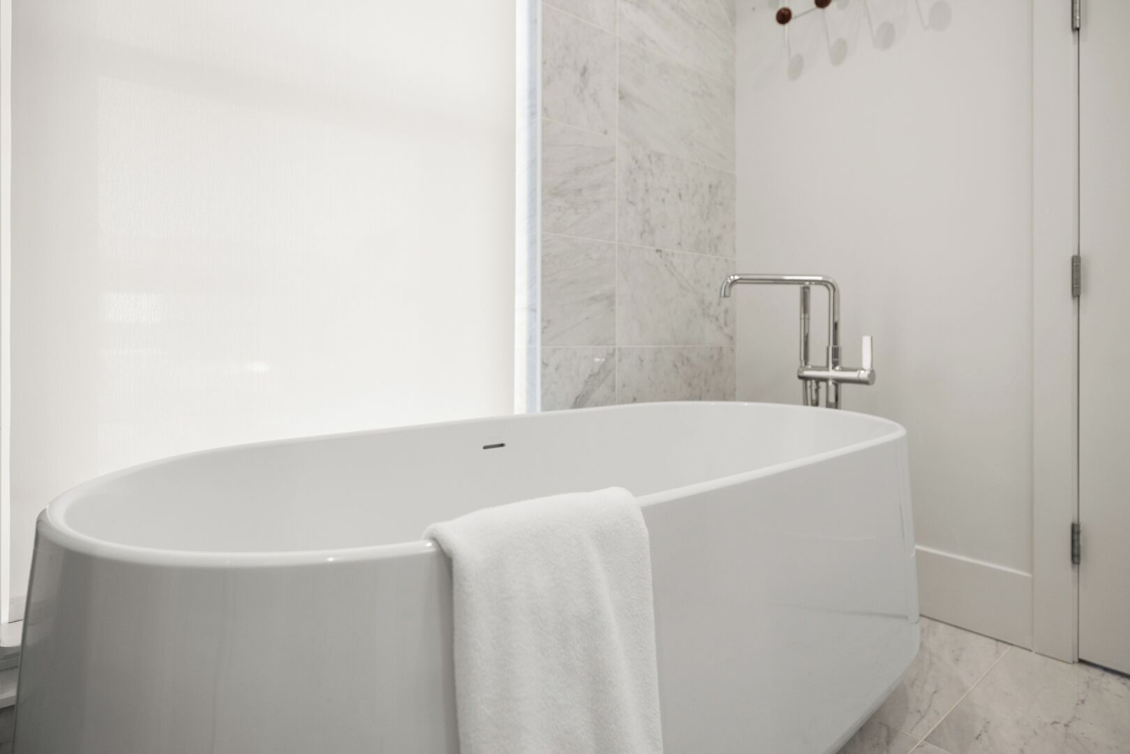Un baño moderno con una bañera independiente, cabina de ducha de vidrio y suelo de mármol.