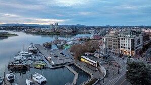 A marina with boats docked, a cityscape with buildings, and a river. - Harbour Heaven (Victoria)