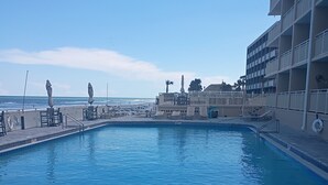 A swimming pool with a view of the ocean and a building with balconies. - Charming apartment in serene Daytona Beach with AC (Daytona Beach)