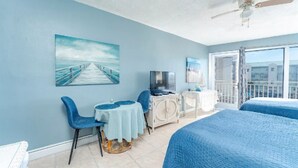 A room with a view of a pier, a television, a desk with a chair, and two beds. - Charming apartment in serene Daytona Beach with AC (Daytona Beach)