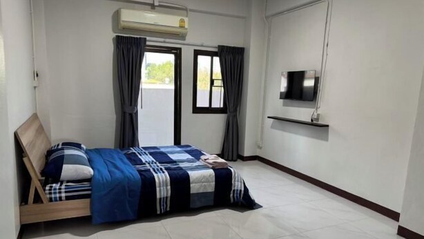 A bedroom with a bed, a TV on the wall, and a window with curtains. - Asleep2 (Bangkok)