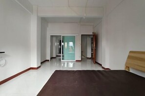 A hotel corridor with a wooden bed frame and a white door at the end. - Asleep2 (Bangkok)