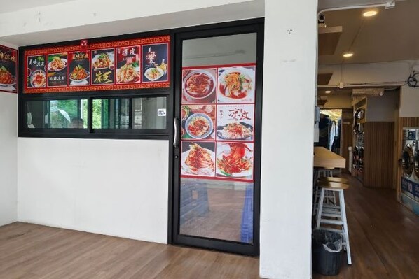 A restaurant interior with a sliding glass door, wooden flooring, and a menu board displaying food items. - Asleep2 (Bangkok)
