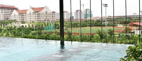 An indoor swimming pool with a view of a sports field and buildings.