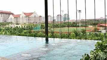 An indoor swimming pool with a view of a sports field and buildings.