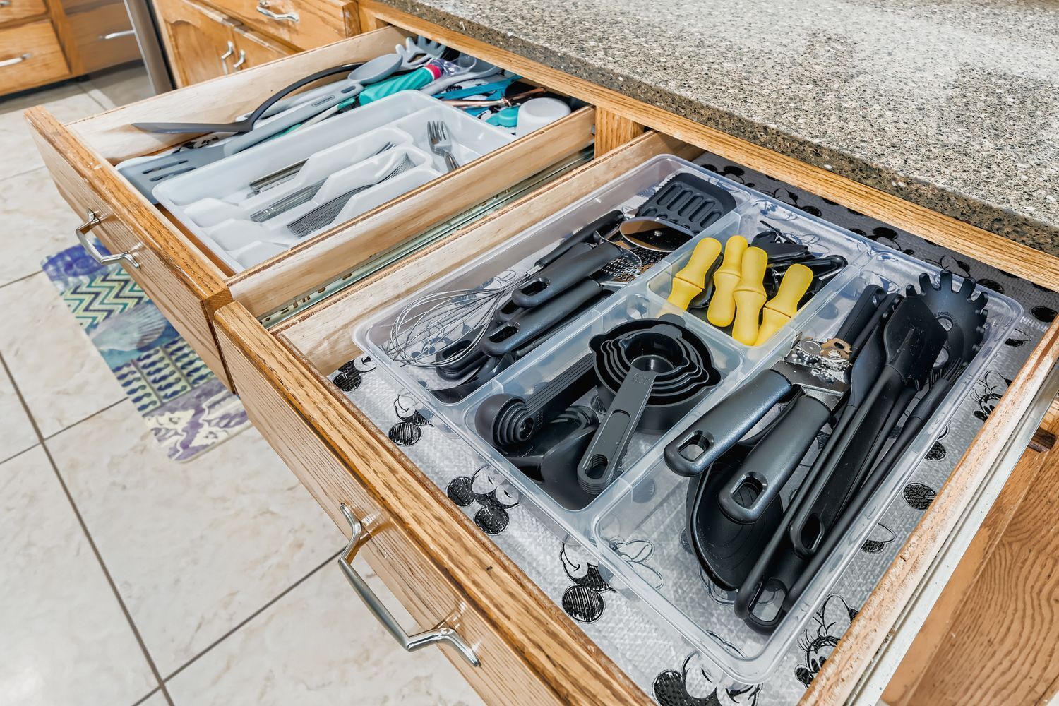 A drawer with kitchen utensils and tools, including knives, a whisk, and measuring cups.