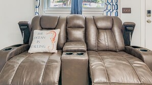 Un sofá de cuero reclinable con un cojín que dice 'The ocean is calling'.
