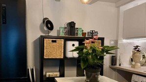 A modern kitchen with a white countertop, a wooden cutting board, a potted plant, and a black cabinet with a woven basket.