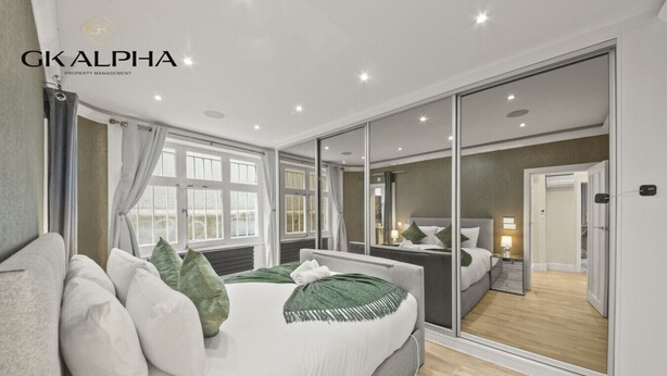 Un dormitorio moderno con una cama grande, un vestidor y vistas a través de las puertas del vestidor.