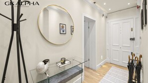 Un interior moderno con una mesa consola de vidrio, un espejo redondo y una puerta con perchero.