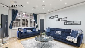 Una sala de estar moderna con dos sofás azules, una mesa de centro de vidrio y una alfombra gris.