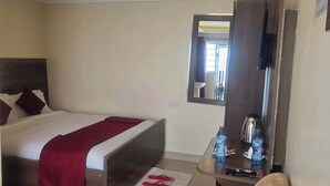 A hotel room with a bed, a sofa, a coffee table, and a mirror. - The Elegant Homes &Accommodation Kericho (Kericho)