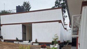 A building with a white exterior, a stone-paved courtyard, and potted plants. - The Elegant Homes &Accommodation Kericho (Kericho)