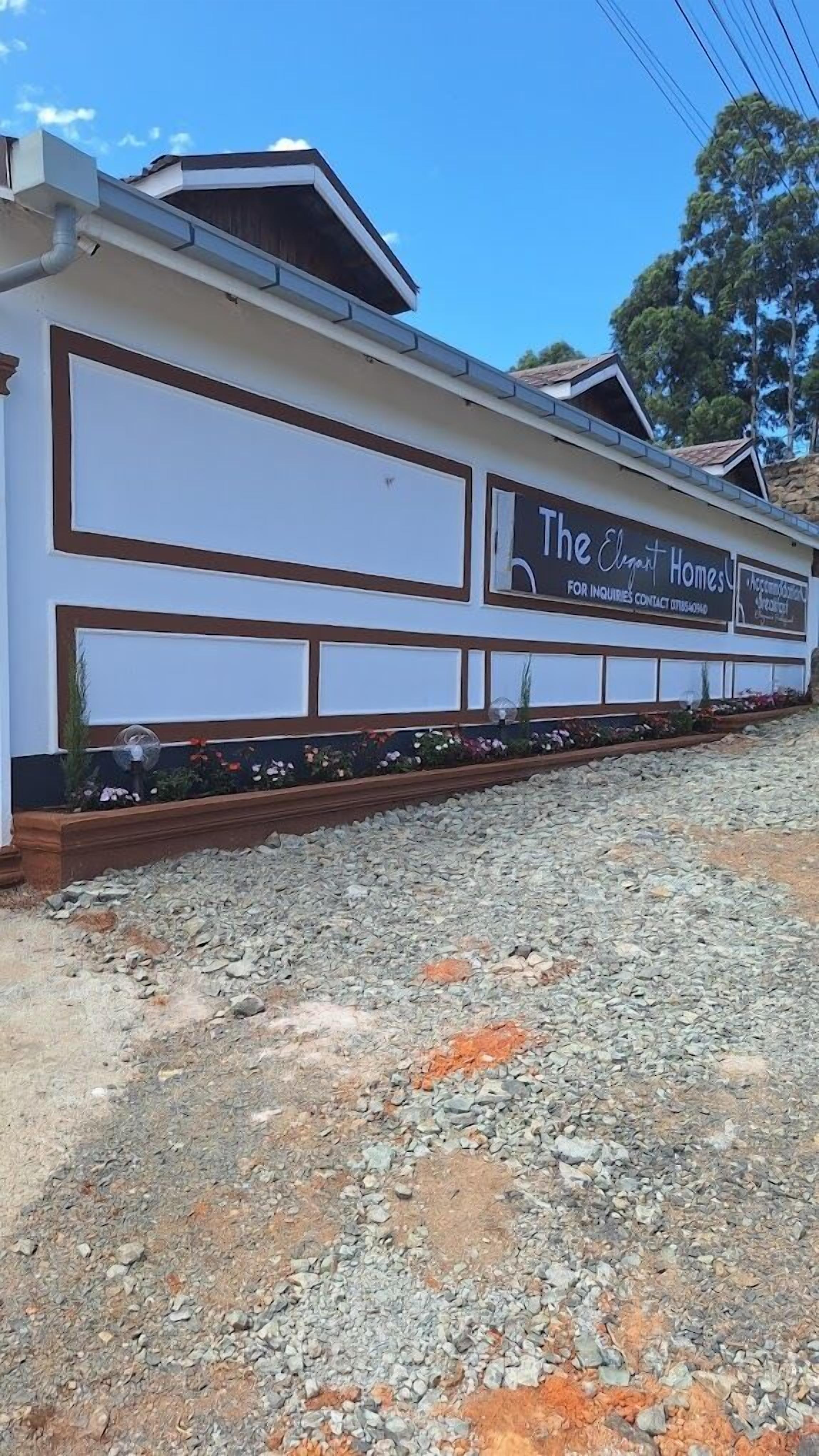 A building with a sign for 'The Elite Homes' and a contact number.