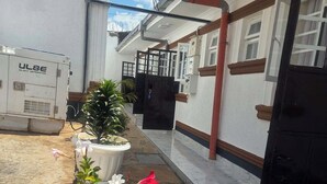 A courtyard with potted plants, a generator, and a building entrance. - The Elegant Homes &Accommodation Kericho (Kericho)