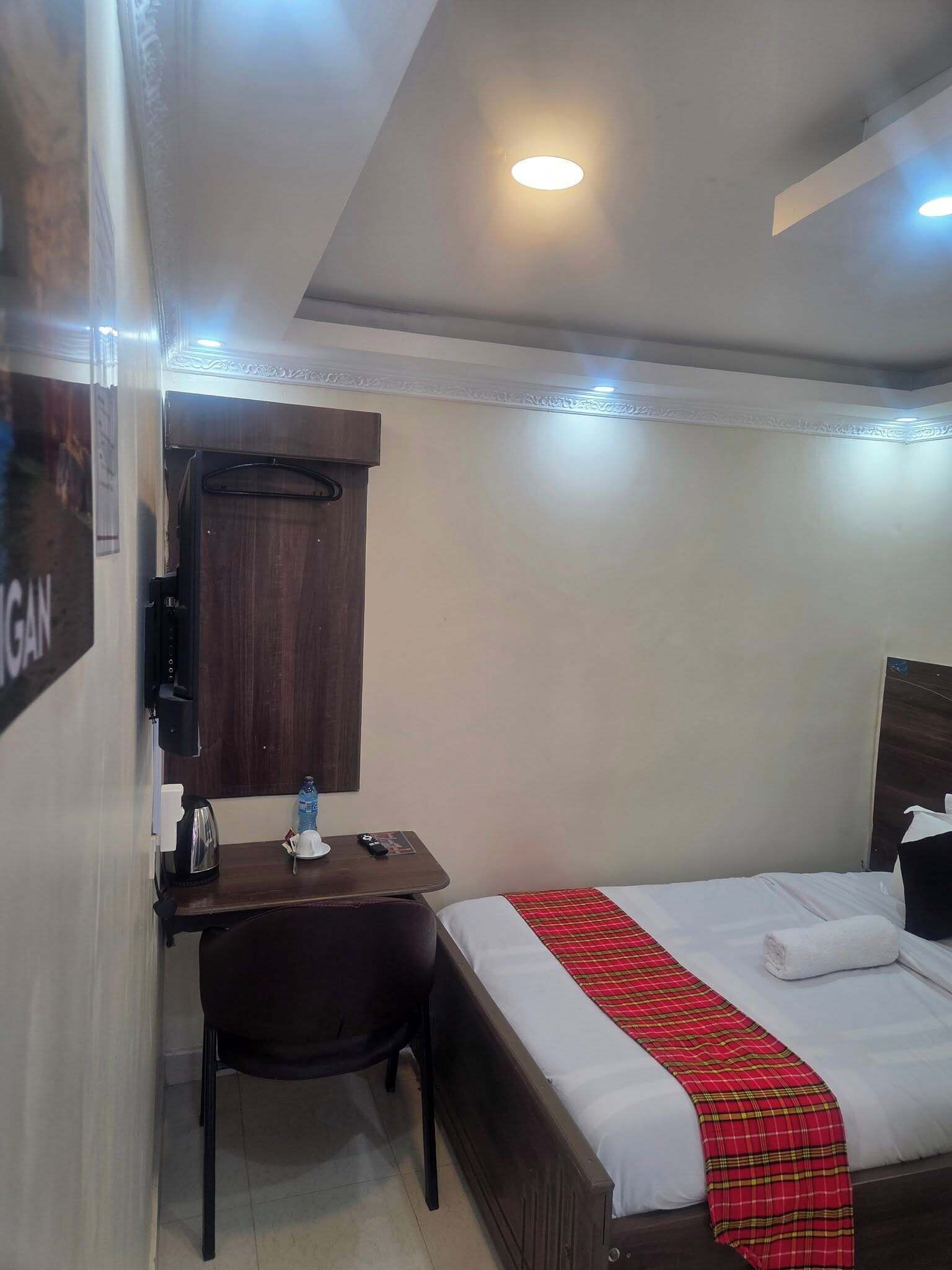 Ein Hotelzimmer mit Bett, Schreibtisch, Stuhl, Kleiderschrank und Spiegel.