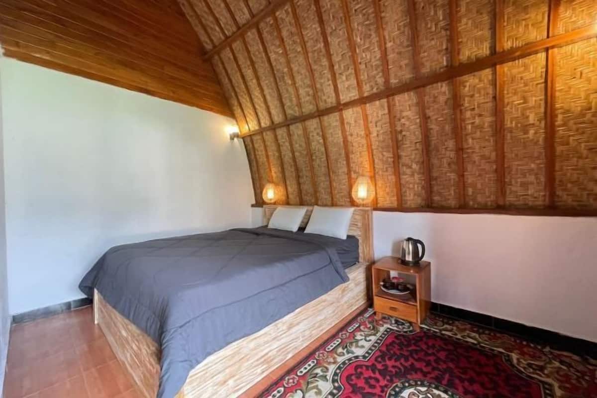 Une chambre à coucher avec un lit, une table de chevet, une bouilloire et un tapis à motifs.