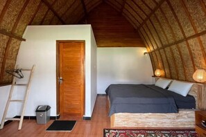 Een gezellige kamer met een bed, een houten trap, een deur en een kleine prullenbak.