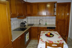 Una cocina con armarios de madera, una encimera, un fregadero y una mesa con frutero.