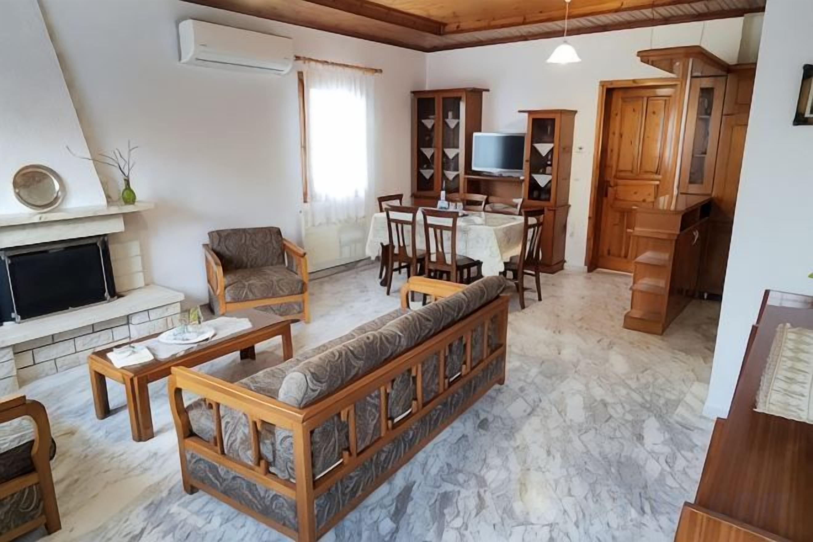 Una sala de estar con chimenea, sofá, mesa de comedor y armarios de madera.