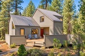 A cabin with a deck, two chairs, and a red door. - Black Butte Ranch House 007 (Sisters)