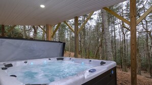 Una vasca idromassaggio con un pontile in legno e uno sfondo boschivo.