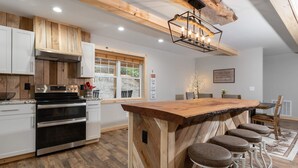 Una cucina moderna con elementi in legno, elettrodomestici in acciaio inossidabile e un'isola centrale con sgabelli da bar.