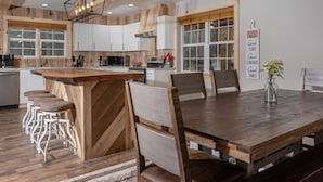 Una cucina moderna con elementi in legno, un'isola centrale con sgabelli da bar e un tavolo da pranzo con sedie.