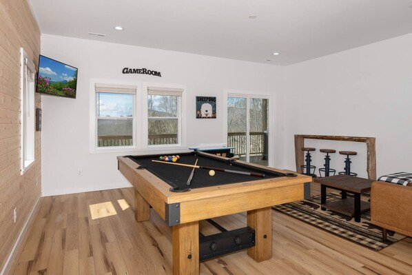 A pool table in a room with a wooden floor, a bar area with stools, and a sign labeled 'GAMEROOM'. - New Cabin 5 Minutes to Boone Long Range Views (Boone)