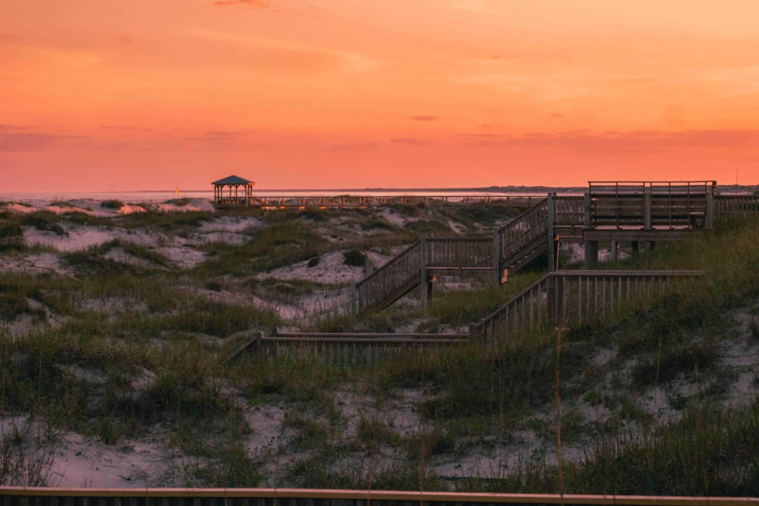 A wooden boardwalk leading to a gazebo over the dunes.