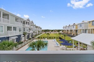 A residential building with a swimming pool, lounge chairs, and a covered patio area.