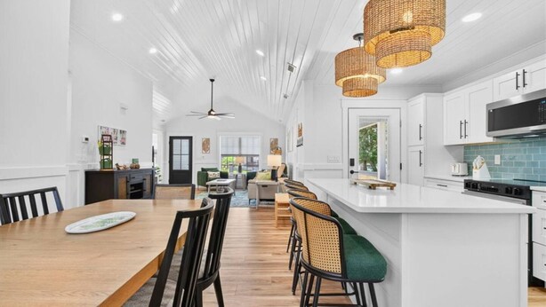 A spacious kitchen with a large island, white cabinetry, and a modern pendant light fixture.